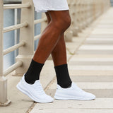 Person wearing white sneakers and black socks on a stone staircase.