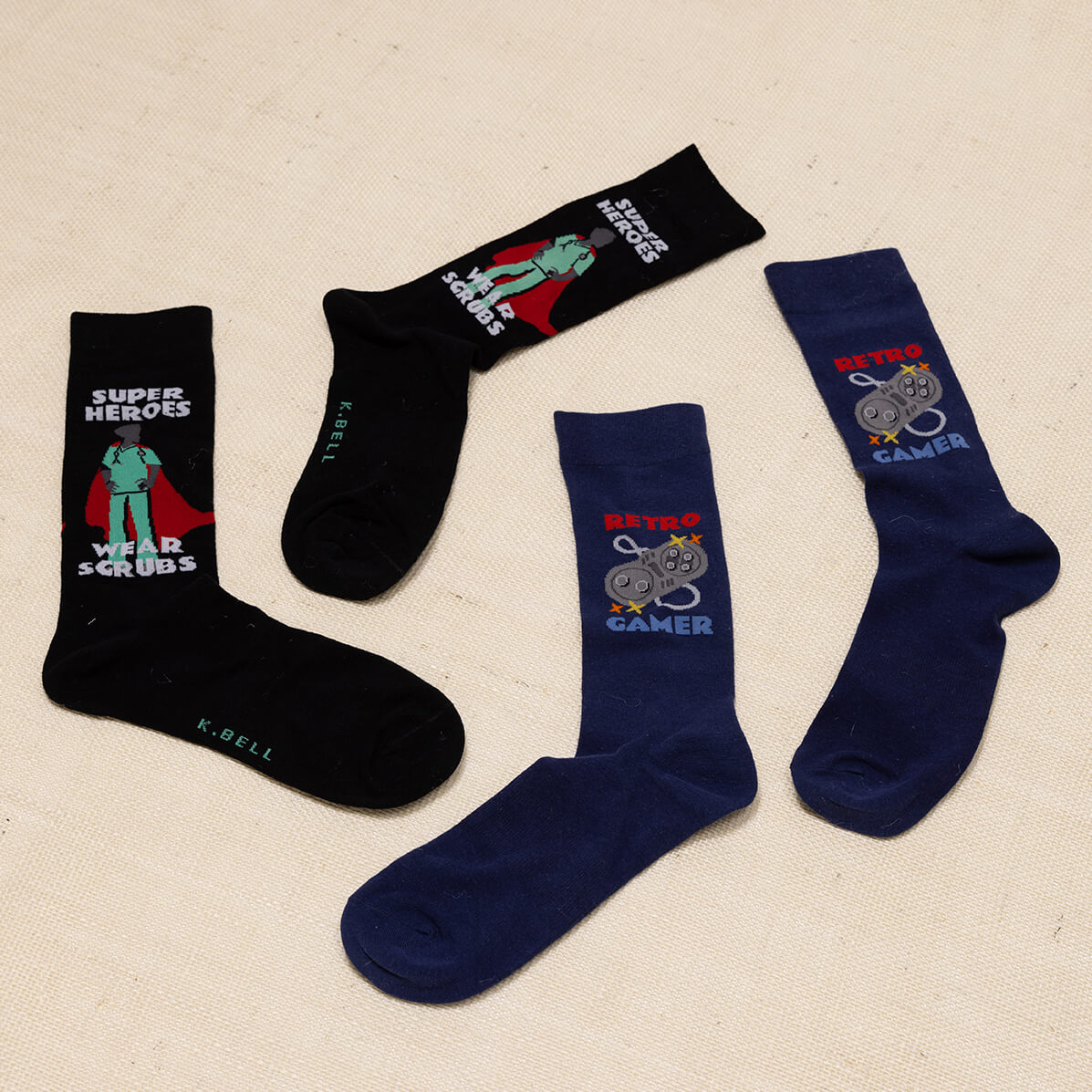 Two pairs of socks with superhero and gaming designs on a beige background