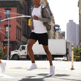 Person in athletic wear crossing a city street with urban buildings in the background thumbnail