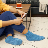 Person wearing blue socks sitting on a patterned rug with a glass of juice on a table. thumbnail