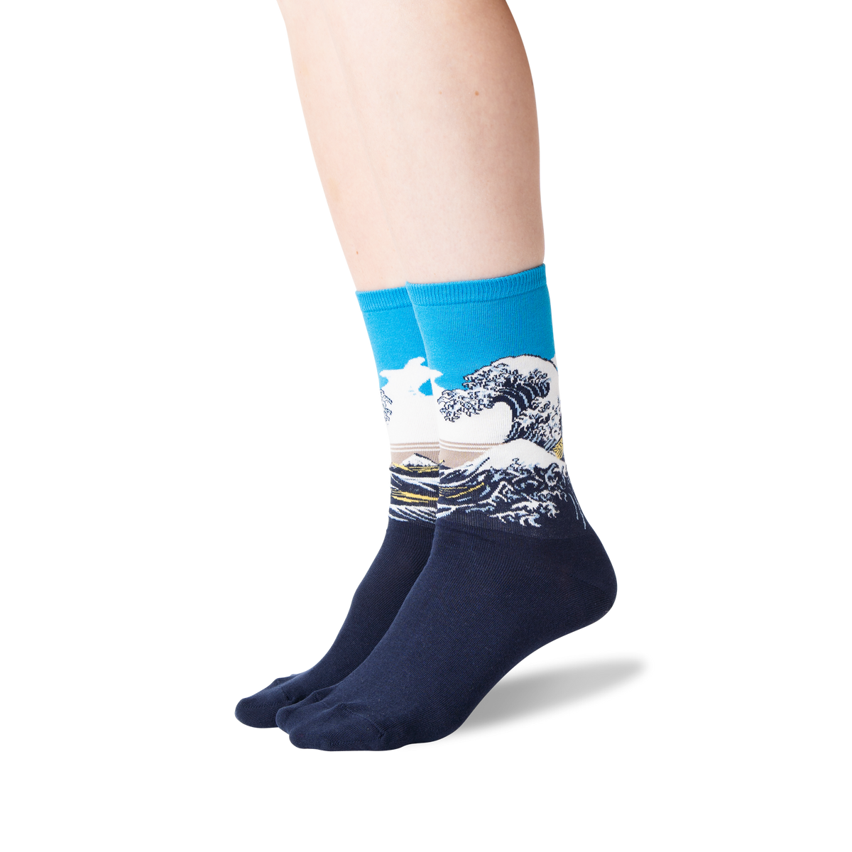 A pair of crew socks worn on a person's feet, featuring a blue cuff and a graphic print of a large ocean wave in the style of Gaudier le Fouler, with a white background.