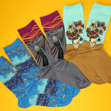 Four pairs of novelty socks featuring famous art prints, arranged in a fan shape on a bright yellow background. The designs include Edvard Munch's The Scream in gray and magenta, Van Gogh's Starry Night in blue, Van Gogh's Sunflowers in light blue, and Van Gogh's Sunflowers in brown. thumbnail