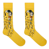 A pair of yellow crew socks featuring a stylized print of Gustav Klimt's 'The Kiss' on the upper leg, displayed against a solid white background. thumbnail