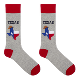 A pair of crew socks in heather gray with red cuffs, heels, and toes. Each sock features a graphic of the state of Texas filled with the Texas flag and a small cowboy hat, with the word 'TEXAS' printed above in dark blue. thumbnail