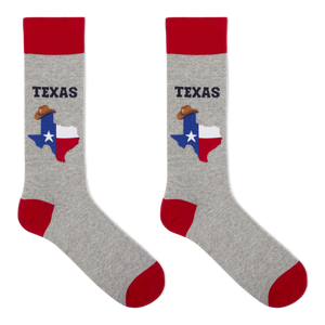 A pair of crew socks in heather gray with red cuffs, heels, and toes. Each sock features a graphic of the state of Texas filled with the Texas flag and a small cowboy hat, with the word 'TEXAS' printed above in dark blue.