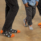 Two people wearing gray socks with colorful Halloween designs on a concrete floor. thumbnail