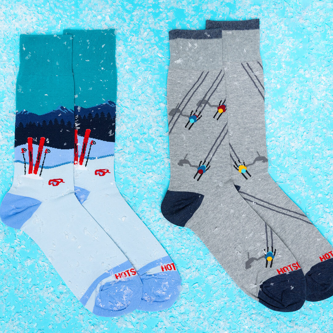 Two pairs of socks with skiing designs on a blue snowy background