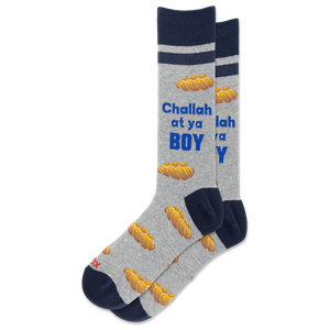 A pair of crew socks in heather gray with navy blue cuffs, heels, and toes, featuring a pattern of golden matzah bread and the text 'Challah at ya BOY' in blue and white.