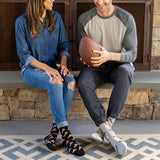 Man and woman sitting on a stone ledge with a football, wearing patterned socks. thumbnail