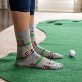 Person wearing gray socks with golf cart design on a putting green thumbnail