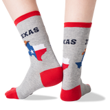 A pair of crew socks worn on feet, shown against a plain white background. The socks are heather gray with red cuffs, heels, and toes, and feature a graphic of the state of Texas with the word 'TEXAS' above it. thumbnail