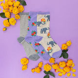 Three pairs of socks with elephant designs on a purple background with yellow flowers. thumbnail