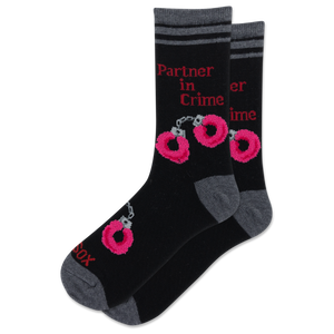 A pair of black crew socks with gray heels, toes, and cuffs, featuring pink and red graphic prints of handcuffs and the text 'Partner in Crime'.