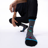 Person wearing gray socks with colorful bug designs on a white background thumbnail