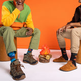 Two people sitting on stools with colorful socks and shoes, wearing patterned socks.