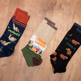 Three pairs of socks with humorous designs on a wooden surface thumbnail