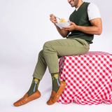 Man sitting on a red and white checkered tablecloth holding a bowl of spaghetti against a white background thumbnail
