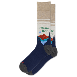 A pair of crew socks with a dark navy blue lower half, gray heels and toes, and a beige upper half featuring a graphic of mountains, pine trees, and the text 'I'd Hike That'.