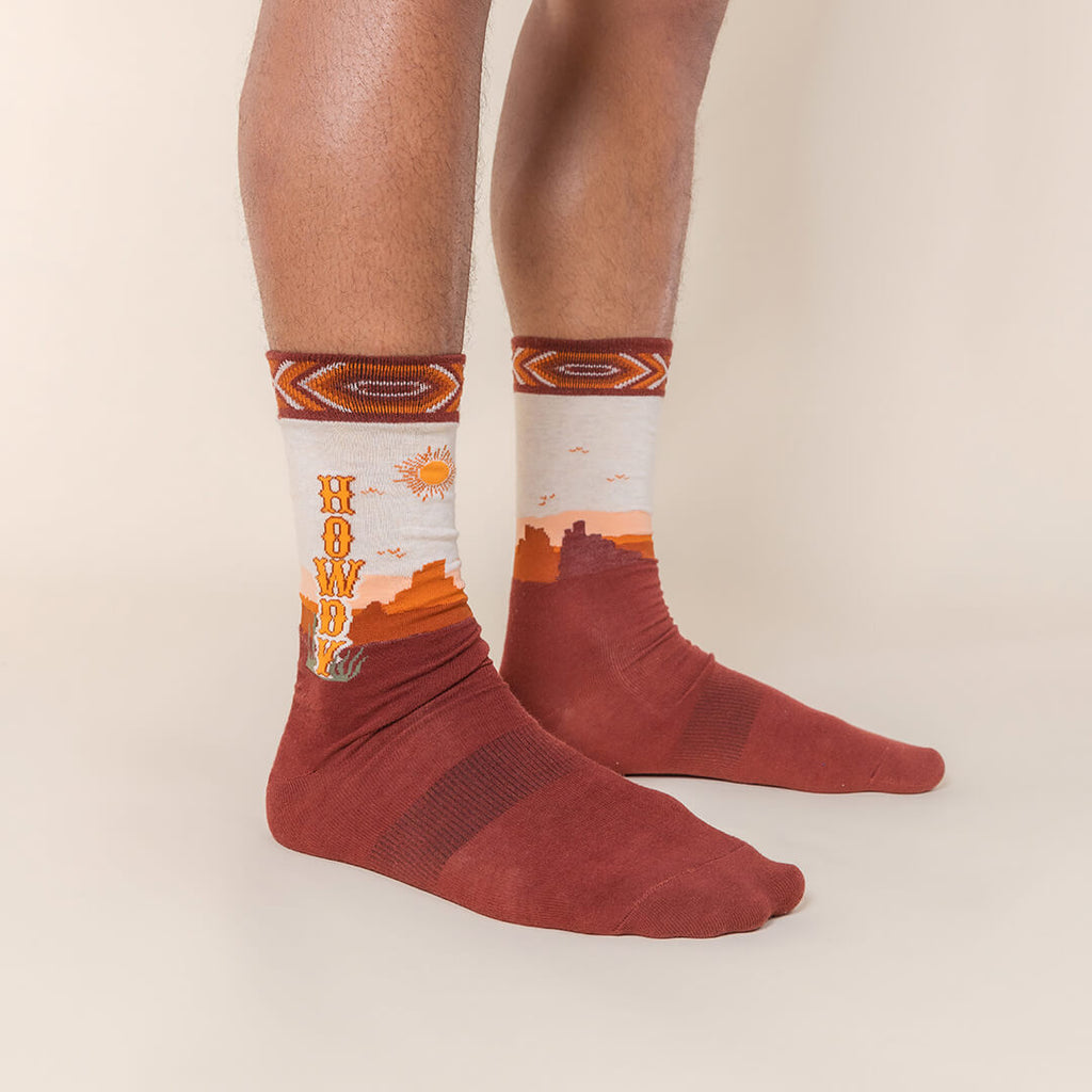 Red socks with desert-themed design on a beige background