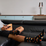 Person sitting on a couch wearing socks with bear designs, holding a remote control. thumbnail