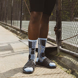 Person wearing black and white striped socks with sandals on a sidewalk. thumbnail