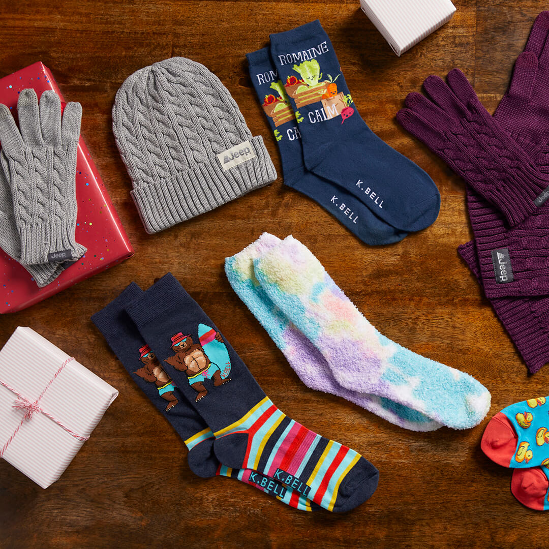 Collection of winter accessories including hats, gloves, and socks on a wooden surface.