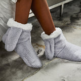 Gray fuzzy bunny slippers with white trim worn by a person on a concrete floor. thumbnail