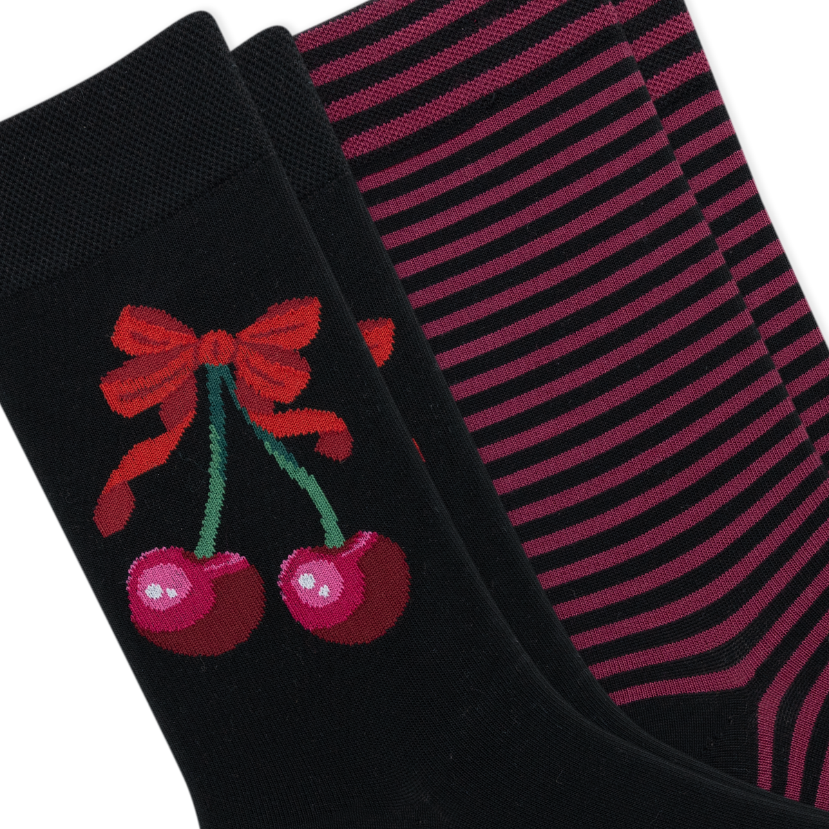 Two pairs of black crew socks arranged diagonally. The front sock features a red bow and two pink cherries with green stems, while the back pair has thin horizontal pink stripes.