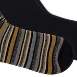 A close-up of a black sock with vertical glittery stripes in gold, gray, and black, and the second sock being solid black, shown against a plain white background.