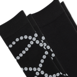 Two pairs of black dress socks stacked diagonally, featuring a textured knit pattern with a silver glittery geometric diamond design on the lower half. thumbnail