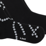 A close-up of a pair of black crew socks with a pattern of small pearl chains, featuring the white text 'k.bell' on the toe area, set against a plain white background. thumbnail