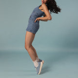 Woman wearing a denim outfit with sneakers and white slouch socks on a light blue background