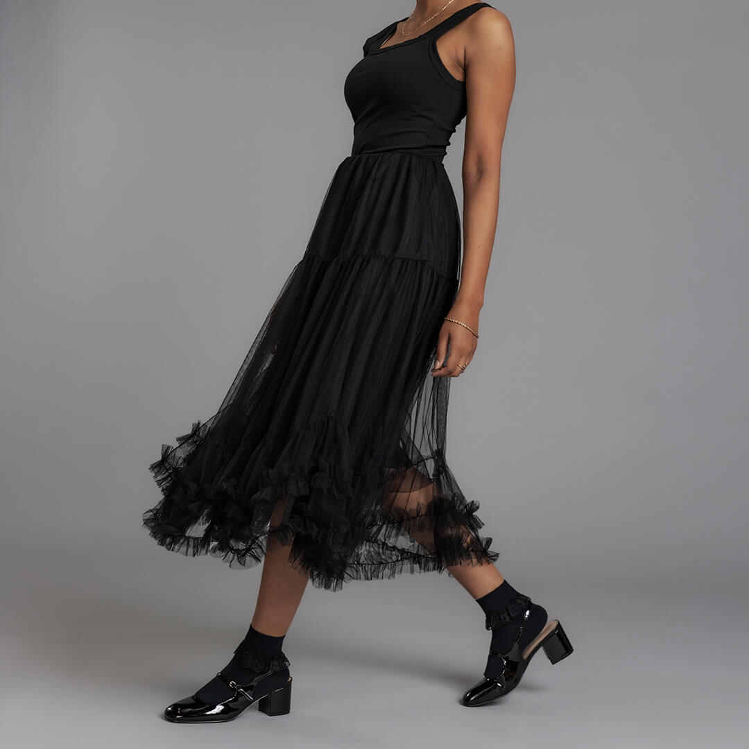 Woman wearing a black dress with sheer overlay on a gray background