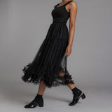 Woman wearing a black dress with sheer overlay on a gray background