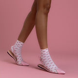Person wearing pink slipper shoes and socks with a pink background