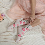 Person wearing floral socks with a pink dress on a textured surface.