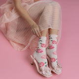 Person wearing floral high-heeled shoes and socks on a pink background thumbnail