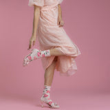 Woman wearing a pink dress and floral high-heeled shoes on a pink background thumbnail