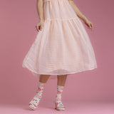Person wearing a pink dress and floral socks on a pink background thumbnail