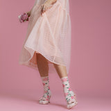 Person wearing a light pink dress and floral socks on a pink background thumbnail