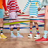 Group of people in bright colored clothes surrounded by ribbons wearing pride-themed socks. thumbnail