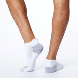 Back profile of a person wearing white MERRELL socks with black and gray accents on the heel and toe.