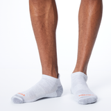 Front profile of a person wearing light gray MERRELL socks with orange and gray accents on the heel and toe