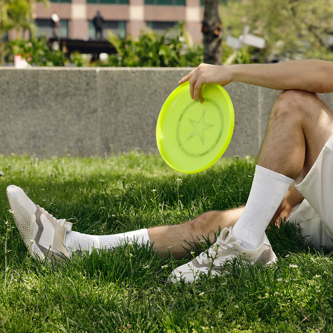 Person sitting on grass holding a yellow frisbee