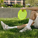 Person sitting on grass holding a yellow frisbee