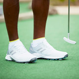 White golf shoes with yellow socks on a green putting surface