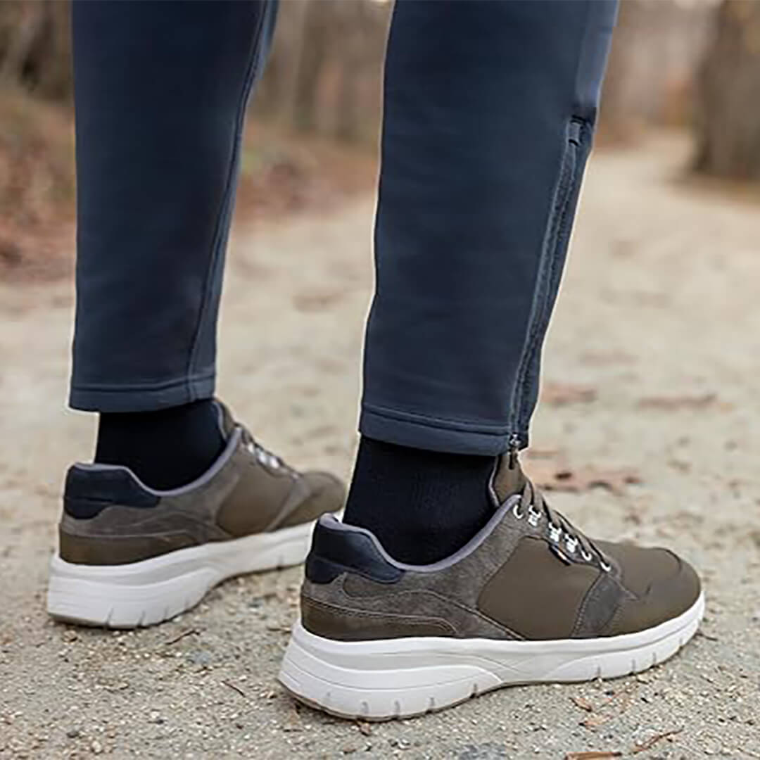 Brown sneakers worn with dark pants on a natural ground surface