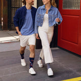 Two people walking on a sidewalk wearing denim jackets and white pants.