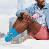 Man sitting outdoors with city skyline, wearing blue socks with hot dog design