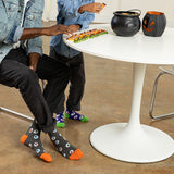 Two people sitting at a table with Halloween-themed decor, including a cauldron and jack-o'-lanterns. thumbnail